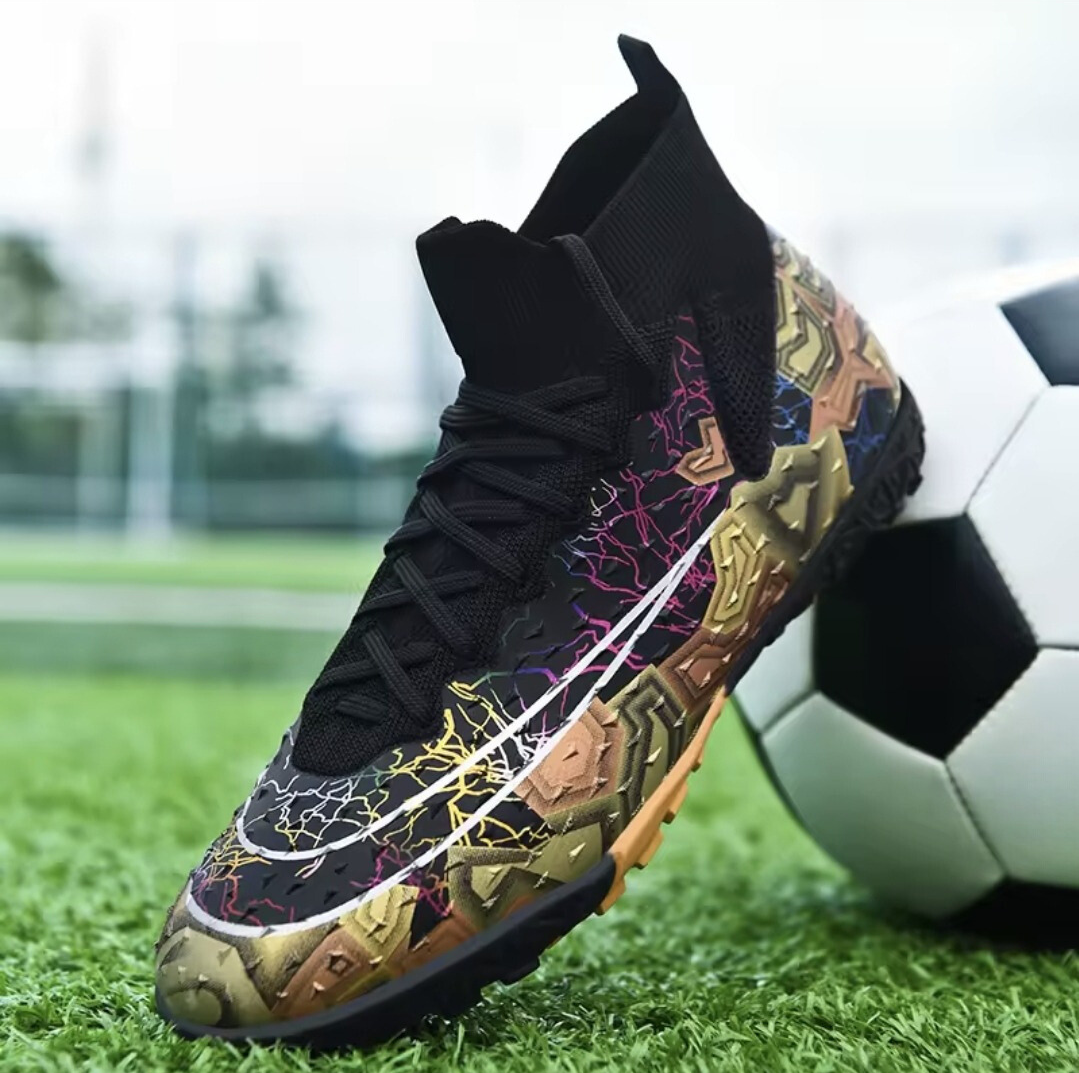Tempesta Men’s Firm Ground Football Boots in black with gold sole and colourful crack details shown on a football pitch next to a ball