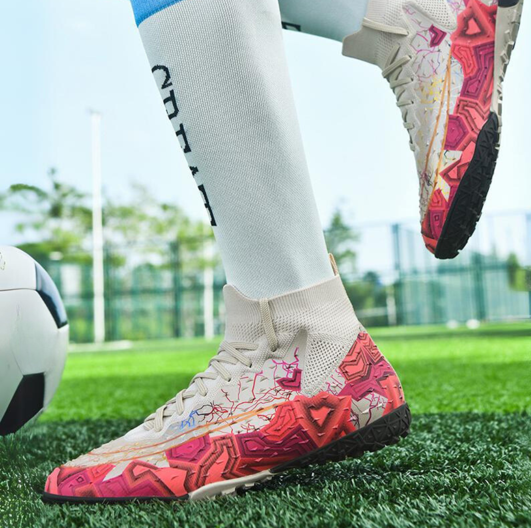 Tempesta Men’s Turf Football Boots in white with pink graphic details worn on artificial grass field with a football in the background