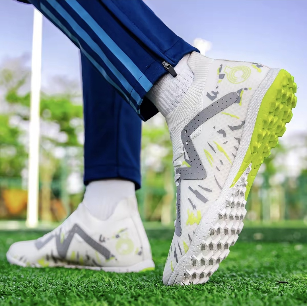 Galactic Men’s Turf Football Boot white patterned on foot next to a football on green artificial grass field background