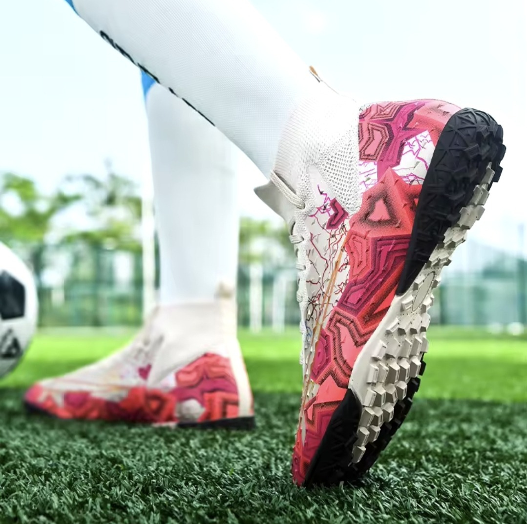 Tempesta Men’s Turf Football Boots in white with pink graphic details worn on artificial grass field with a football in the background
