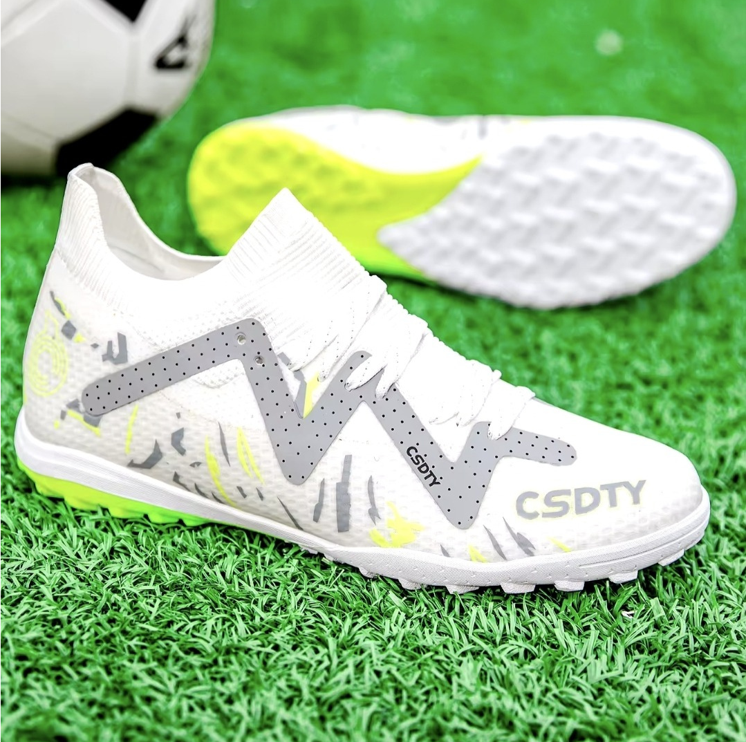 Pair of Galactic Men’s Turf Football Boots white patterned next to a football on green artificial grass field background