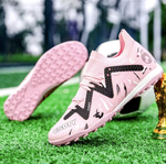 Pair of Galactic Men’s Turf Football Boots pink patterned next to a football on green artificial grass field background