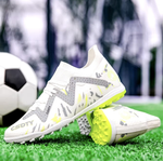 Pair of Galactic Men’s Turf Football Boots white patterned next to a football on green artificial grass field background