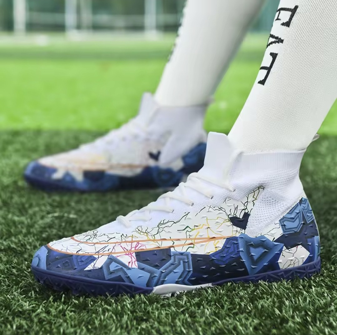 Tempesta Men’s Turf Football Boots in white with blue graphic details worn on artificial grass field with a football in the background