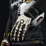 Goalkeeper holding football with Elite Sport Pro Calavera gloves featuring skeleton and floral details on black background