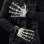 Football goalkeeper wearing Elite Sport Pro Calavera gloves adjusting wrist strap on black patterned background
