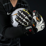 Goalkeeper holding football with Elite Sport Pro Calavera gloves featuring skeleton and floral details on black background