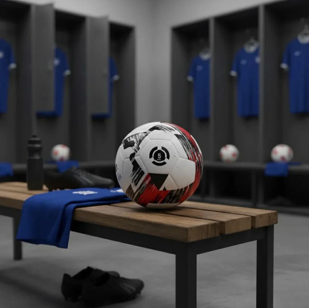 Football on a wooden bench inside a locker room with blue football kits hanging.