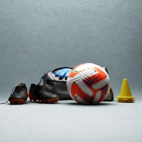 Vector football alongside football gear: boots, sports bag, and training cones.